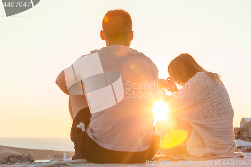 Image of Couple watching sunrise and taking vacation photos at Santorini island, Greece.