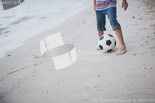 Image of Young little boy playing on the beach with soccer ball. 