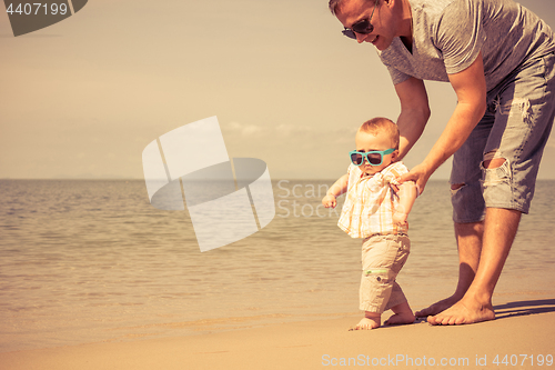 Image of Father and baby son playing on the beach at the day time.