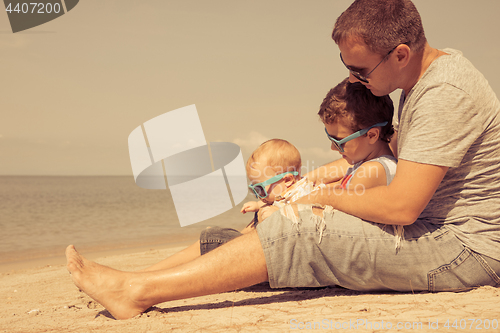 Image of Father and children  playing on the beach at the day time.