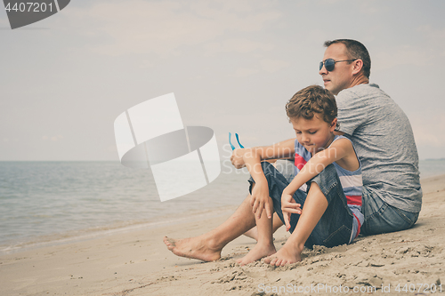 Image of Portrait of young sad little boy and father sitting outdoors at 