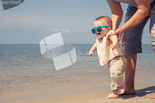 Image of Father and baby son playing on the beach at the day time.