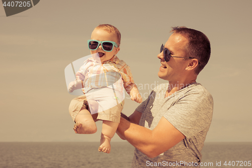 Image of Father and baby son playing on the beach at the day time.