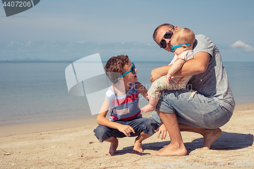 Image of Father and children  playing on the beach at the day time.