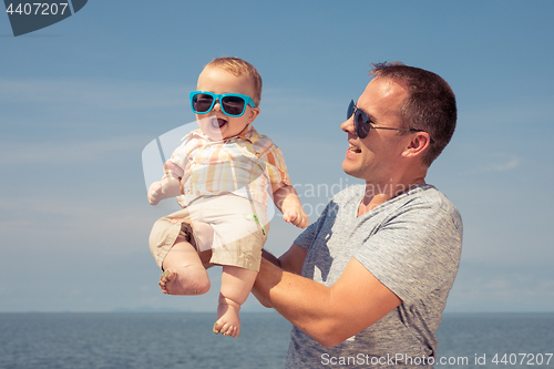 Image of Father and baby son playing on the beach at the day time.