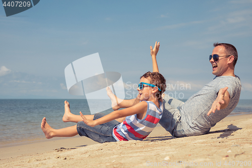 Image of Father and son  playing on the beach at the day time.