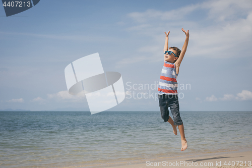 Image of One happy little boy playing on the beach at the day time.