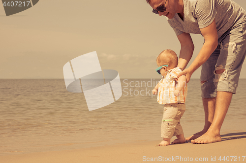 Image of Father and baby son playing on the beach at the day time.