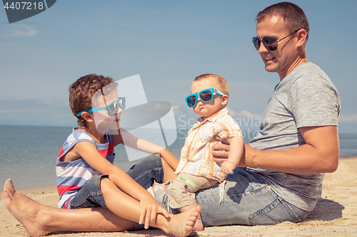 Image of Father and children  playing on the beach at the day time.