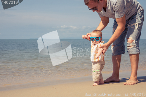 Image of Father and baby son playing on the beach at the day time.