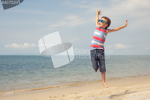 Image of One happy little boy playing on the beach at the day time. 