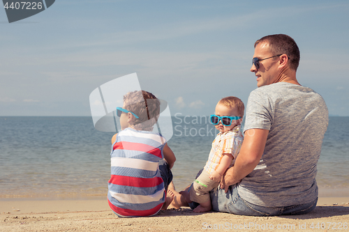 Image of Father and children  playing on the beach at the day time.