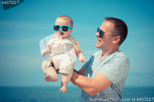 Image of Father and baby son playing on the beach at the day time.