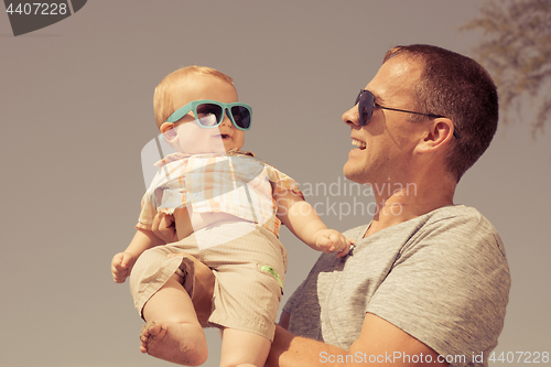 Image of Father and baby son playing on the beach at the day time.