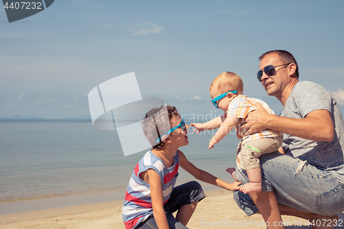 Image of Father and children  playing on the beach at the day time.