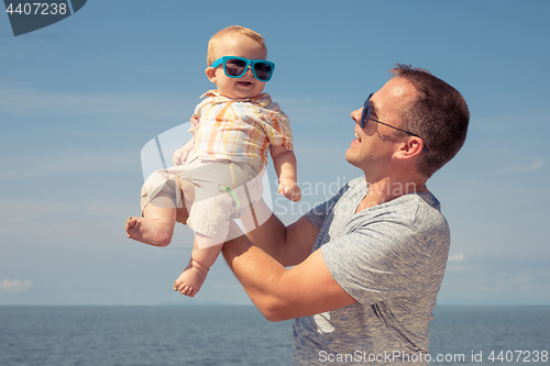 Image of Father and baby son playing on the beach at the day time.