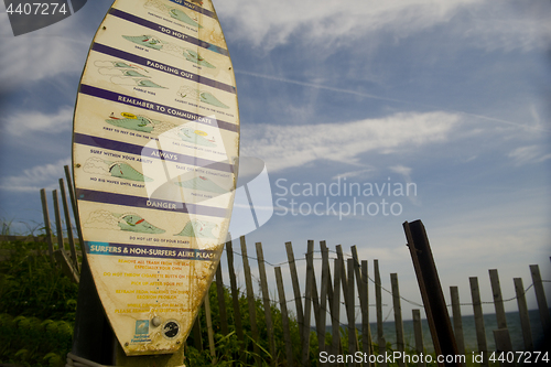 Image of editorial surfer rules on surf board with Ditch Plains beach bac