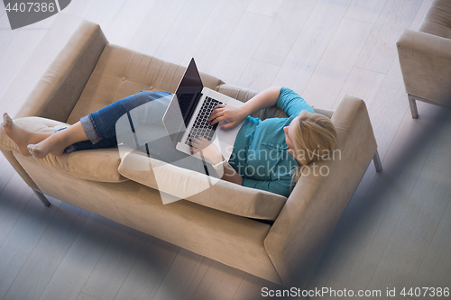 Image of Young woman using laptop at home