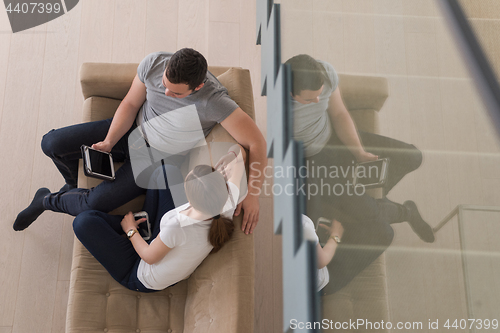 Image of couple relaxing at  home with tablet computers