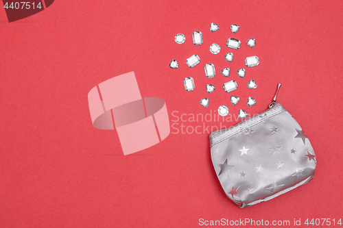 Image of Silver purse and precious stones on bright pink background