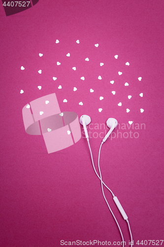 Image of Earphones and hearts on bright magenta background