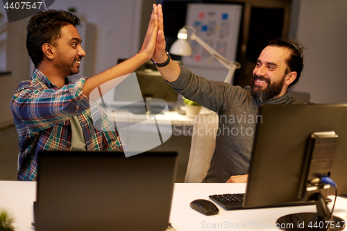 Image of creative team making high five at night office