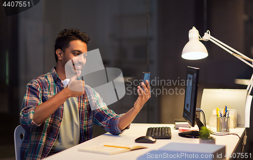 Image of man with smartphone having video call at office