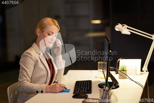 Image of businesswoman calling on sartphone at night office