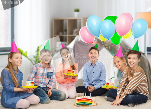 Image of happy children in party hats with birthday cake