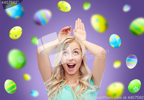 Image of happy woman making bunny ears over easter eggs