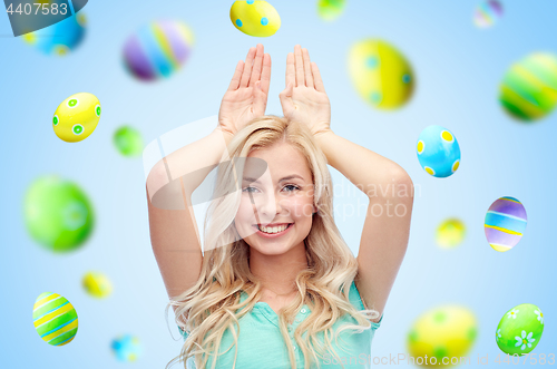 Image of happy woman making bunny ears over easter eggs