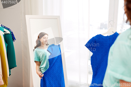 Image of pensive plus size woman with blue dress at mirror