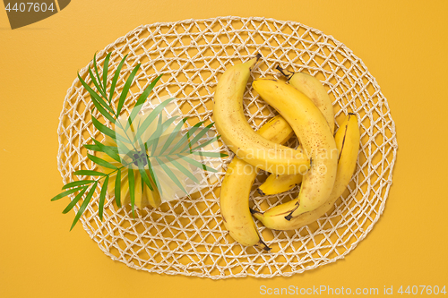 Image of Ripe bananas and palm leaves on yellow background