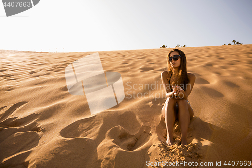 Image of Young girl sitting on a sand dune