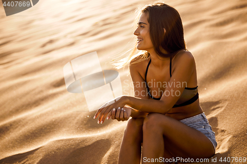 Image of Young girl sitting on a sand dune