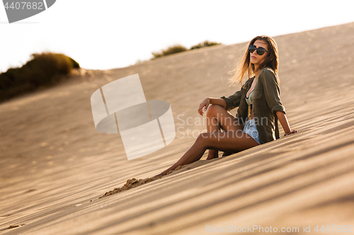 Image of Young girl sitting on a sand dune