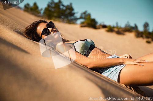 Image of Young girl lying on a sand dune