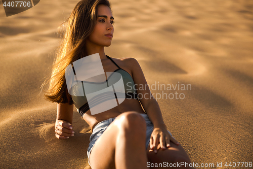 Image of Young girl lying on a sand dune
