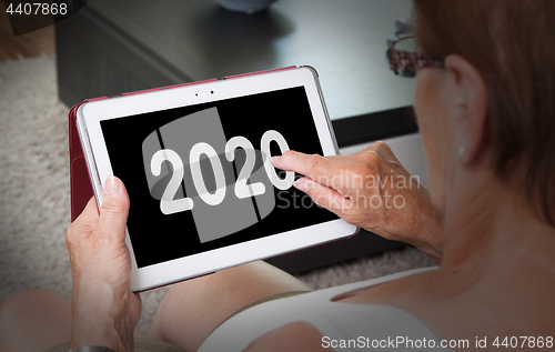 Image of Senior lady relaxing and her tablet - 2020