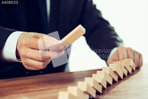 Image of Man and wooden cubes on table. Management concept