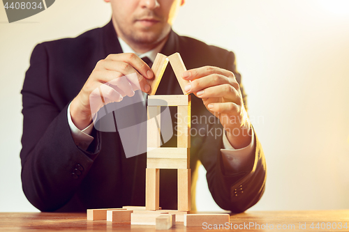 Image of Man and wooden cubes on table. Management concept