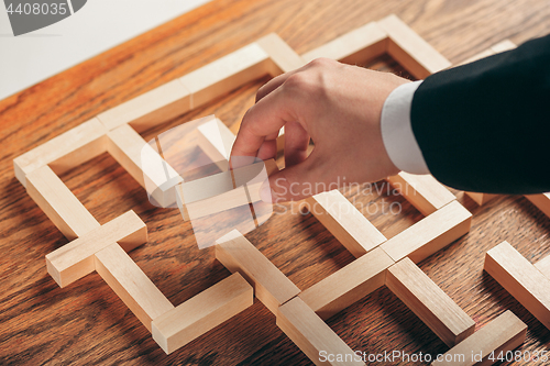 Image of Man and wooden cubes on table. Management concept