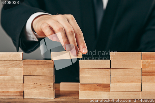 Image of Man and wooden cubes on table. Management concept