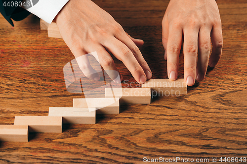 Image of Man and wooden cubes on table. Management concept