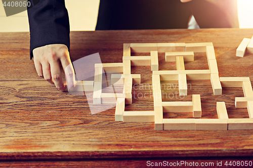 Image of Man and wooden cubes on table. Management concept