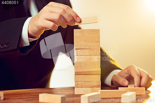 Image of Man and wooden cubes on table. Management concept