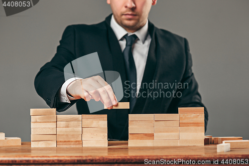 Image of Man and wooden cubes on table. Management concept