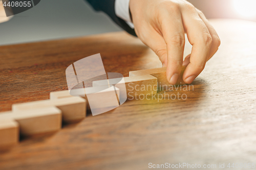 Image of Man and wooden cubes on table. Management concept