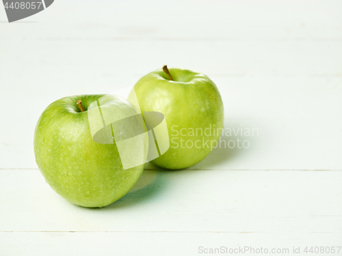 Image of Shot of two fresh green apples with green leaf on a table.