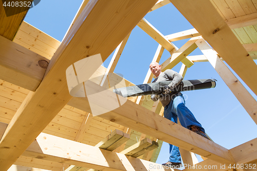 Image of Builder at work with wooden roof construction.